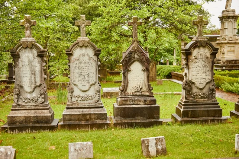 Four weathered stone tombstones at Historic Oakland cemetery. 