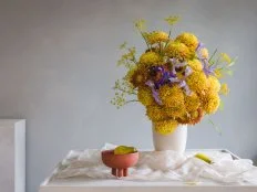 Atlanta-based floral designer Skye Lin creates floral arrangements infused with cultural specificity and sustainable use of foraged elements. For this fall arrangements she blended chrysanthemums in a variety of colors, foraged yellow Queen Anne's lace and iris for a simple but lush effect. A plain matte white vessel adds a rustic touch.