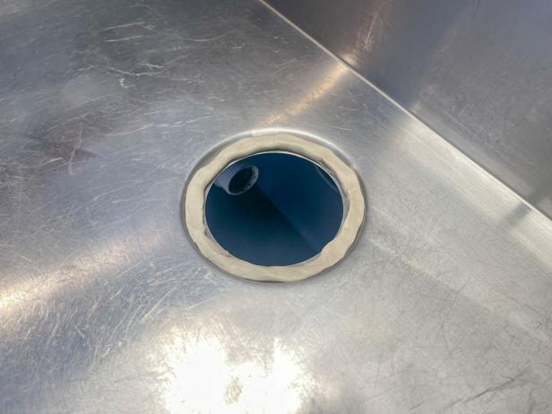The next step in installing a garbage disposal is to apply a new bead of plumber's putty around the sink drain.