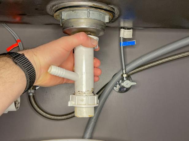 The next step in installing a garbage disposal is to remove the sink tailpiece from the drain flange.