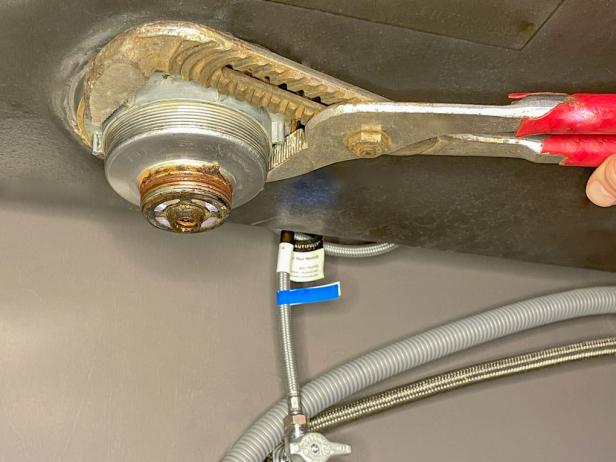 The next step in installing a garbage disposal is to remove the drain flange using tongue-and-groove pliers.