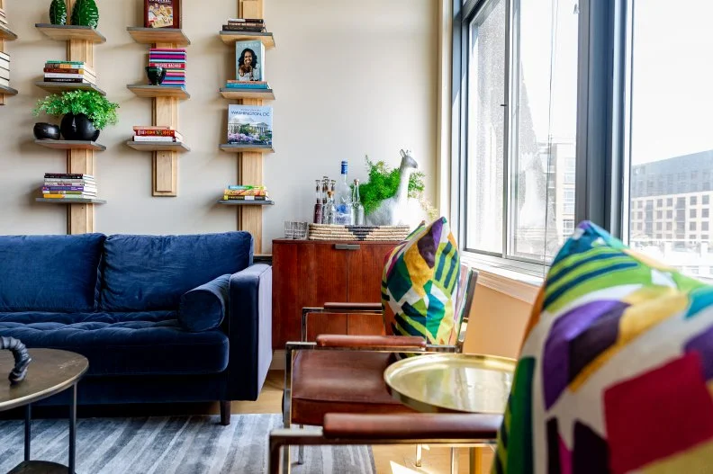 A photo of a living room with a blue sofa and brown chairs.