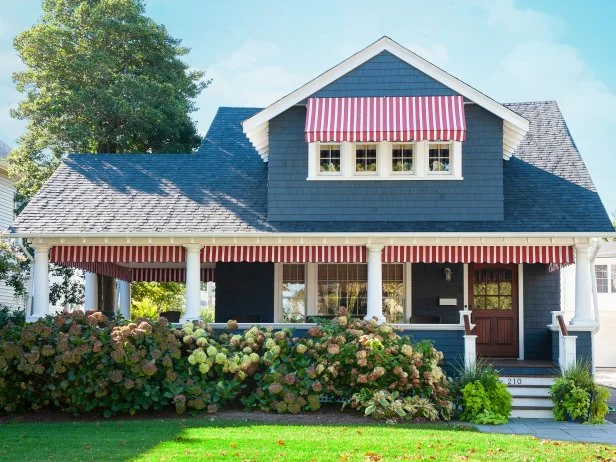 Dark Blue Home With Striped Awnings on the Windows and Porch