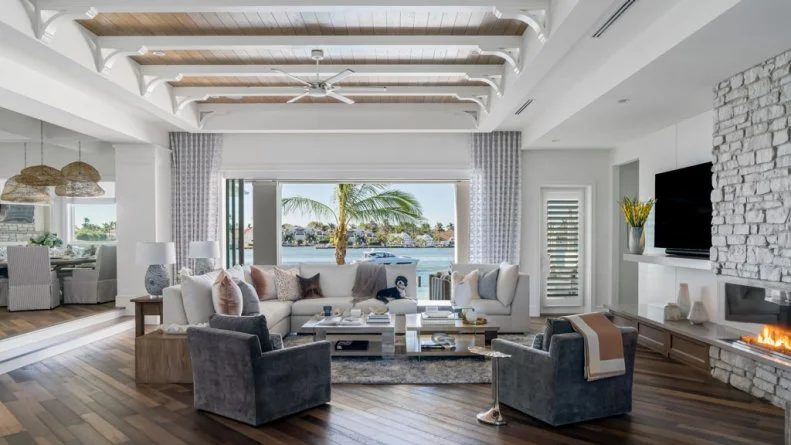 White Coastal Living Room That Opens Onto Waterfront Patio