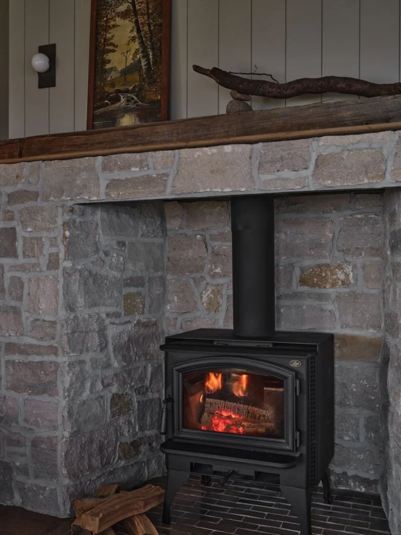 Wood-Burning Stove Inside Stone Fireplace Surround