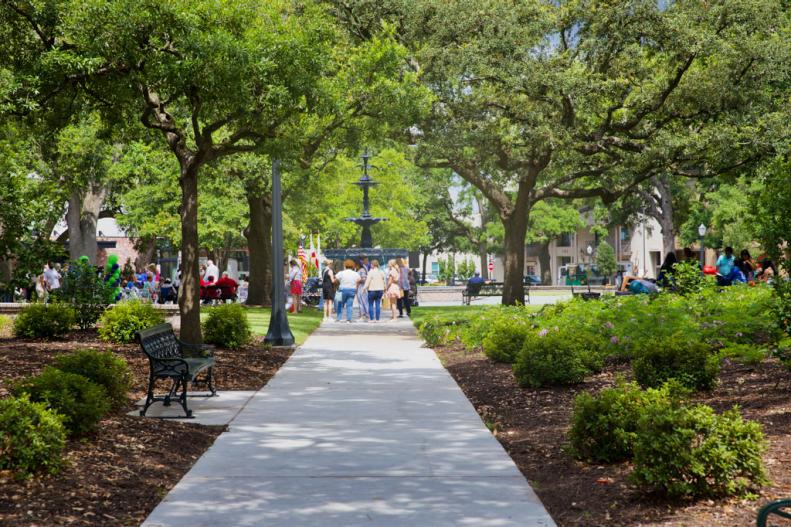 A view of trees, a path, people and a cast iron fountain in Bienville Square in Mobile