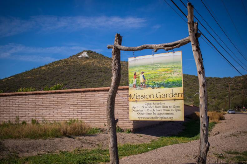 A sign in front of an adobe wall around Mission Garden in Tucson, Arizona