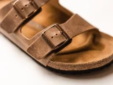 Chicago, IL - 4/9/20: Brown leather Birkenstock cork sandals sitting on a minimal white background