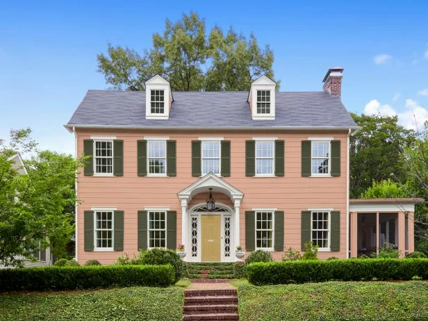 Pink Colonial House With Green Shutters and a Muted Yellow Door