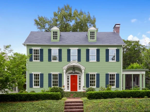 Green Colonial House With Navy Shutters and a Red Front Door