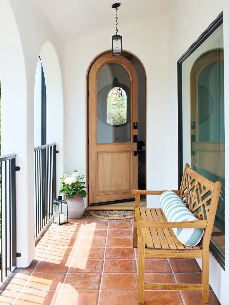 Arched Front Door With Terra Cotta Entry Tiles and a Bench