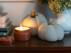 Two concrete pumpkins sitting on a table with a candle