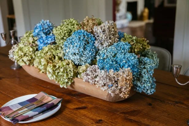 Dried hydrangeas in a variety of colors are displayed on a table.