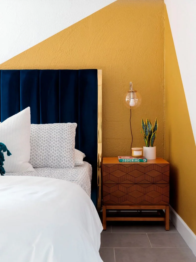 Yellow and White Bed Room With a Blue Velvet Headboard