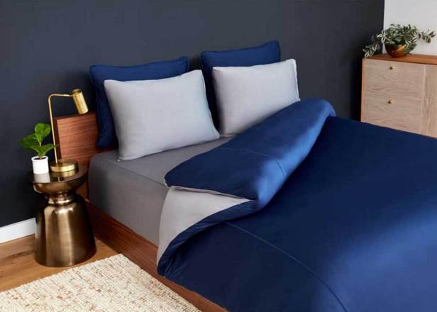 Bedroom features neatly made bed with navy and gray bedding