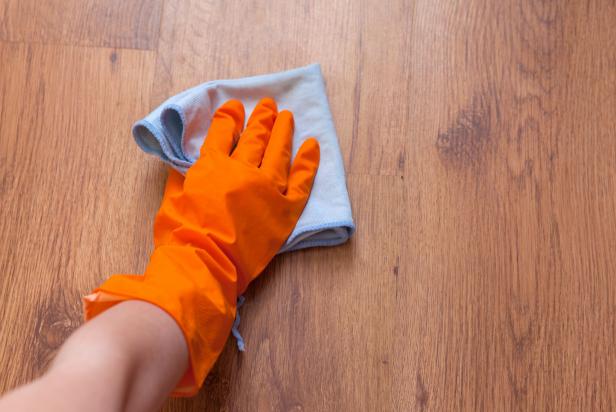 A woman hand Using blue rags wipe the wooden floor.