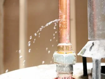 Water leaking out of a pipe on top of a water heater.