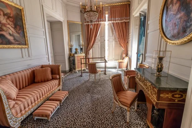 Room inside Versailles' Trianon Palace with coral striped sofa and coral curtains.