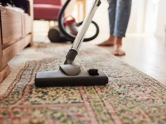 Shot of a young woman vacuuming the living room at home