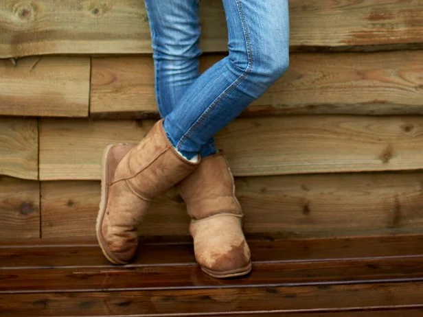 Full length portrait of confident woman standing arms crossed against wooden wall