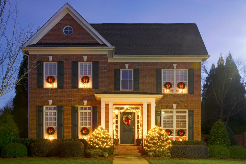 Brick Home with Christmas Lights on Door and Bushes 