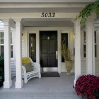 White Covered Porch With Black Front Door