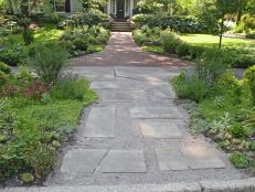 Landscaper Bobbie Schwartz created a memorable entrance to this Ohio home by turning the hellstrip area into drought tolerant gardens separated by a permeable path from the street to the front walkway.&nbsp;