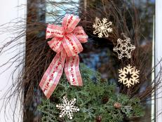 To make this wreath you will need: A twig wreath/ribbon/wooden snowflake ornaments/greenery/pinecones/twine/scissors/floral wire/hot glue gun