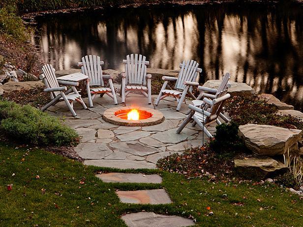 A small fire pit embedded in a stone patio and circled by wooden chairs creates a rustic feel.