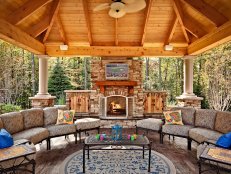 A spacious, covered gazebo is ready for multi-seasonal use by offering a fireplace, ceiling fan, two sofas, a mounted TV and surround sound.