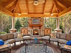 A spacious, covered gazebo is ready for multi-seasonal use by offering a fireplace, ceiling fan, two sofas, a mounted TV and surround sound.