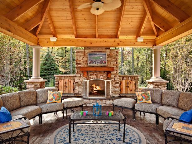 A spacious, covered gazebo is ready for multi-seasonal use by offering a fireplace, ceiling fan, two sofas, a mounted TV and surround sound.