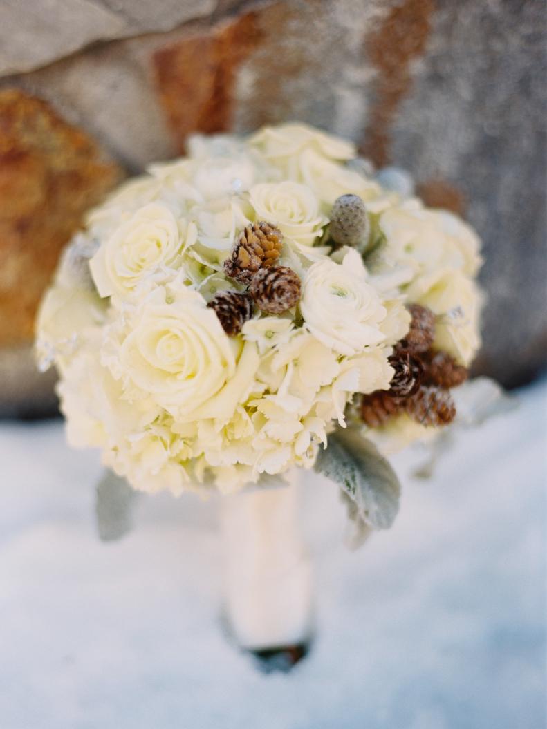 Pinecones mixed with white roses make a wonderfully woodsy wedding bouquet.&nbsp;
