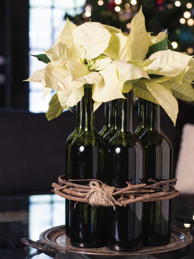 Upcycle wine bottles to make a festive vase for light poinsettia blossoms for your holiday decor.