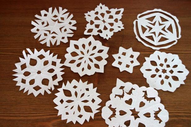Let it snow indoors this year with a flurry of hand crafted snowflakes. Supplies needed include: white paper, pointy scissors, glitter, satin Mod Podge, foam brush, craft paper.