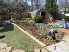 Here you can see the landscape timbers set into place. We drilled holes with a long drill bit and sledge-hammered in 18&quot;-24&quot; long pieces of rebar in three places on each beam to secure them into the hillside. The beams create a nice transition between the grass and the mulch bed and the kids use them as balance beams.