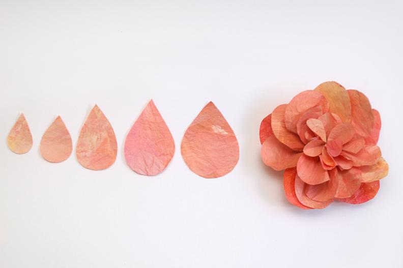 These layered flowers were inspired by roses and peonies. They make great anchor flowers for your cake topper because they are easy to make full and large, just add more petals! Begin by cutting tear drop shaped petals in your chosen color. How many and how large your petals should be will depend on how big you want your final rose to be. For a large one try 5 different sizes with about 7 petals in each size.