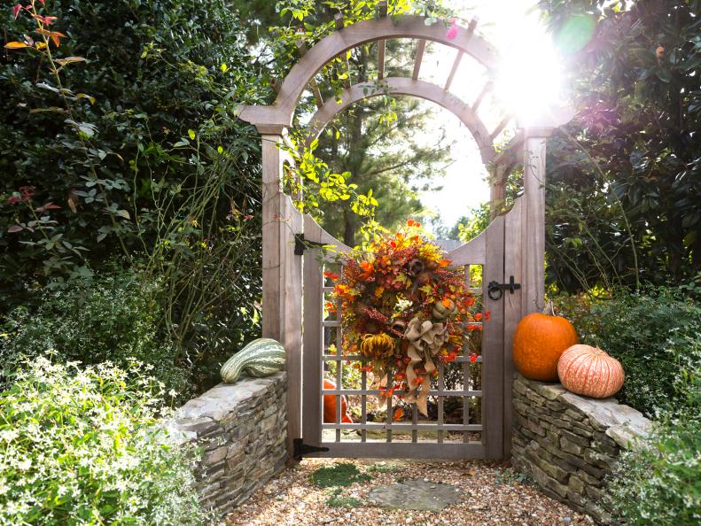 A wreath of dried fall flowers and foliage adorns the gate to a side entrance to the garden, accented by pumpkins and squashes.