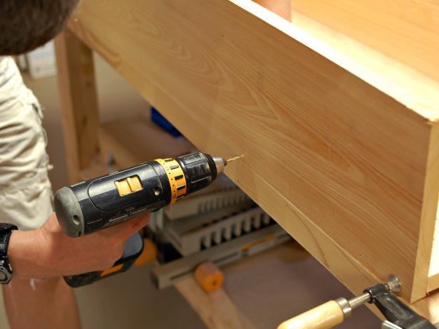 Use drill to attach parts of window box together with screws along length of box.