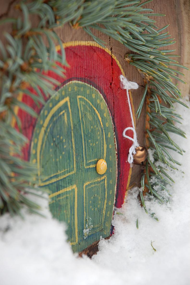 Little details make your fairy house extra special, so don't be afraid to go overboard. We created a doorbell by hanging a little jingle bell by the front door, and created a little garland of fresh evergreen branches to hang over the door.