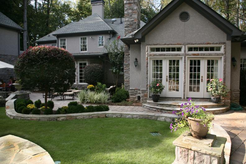 The curved walls were a design element the homeowners saw on visits to Charleston and wanted to bring into their Georgia yard. The stone is from south Georgia, which ties into the stone details on the European-style home. The Zeon zoysia grass, with its fine texture, can handle sun and shade.