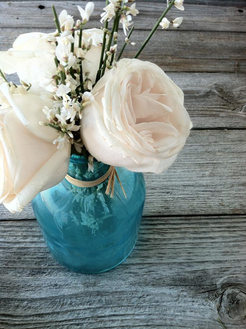 A beautiful bunch of white roses and white genista fill a blue bottleneck vase. Designed by <a target="_blank" href="https://www.thebouqs.com/en/64-all?bcid=1235&amp;utm_medium=partnerships&amp;utm_source=hgtv&amp;utm_campaign=hg...">The Bouqs</a>