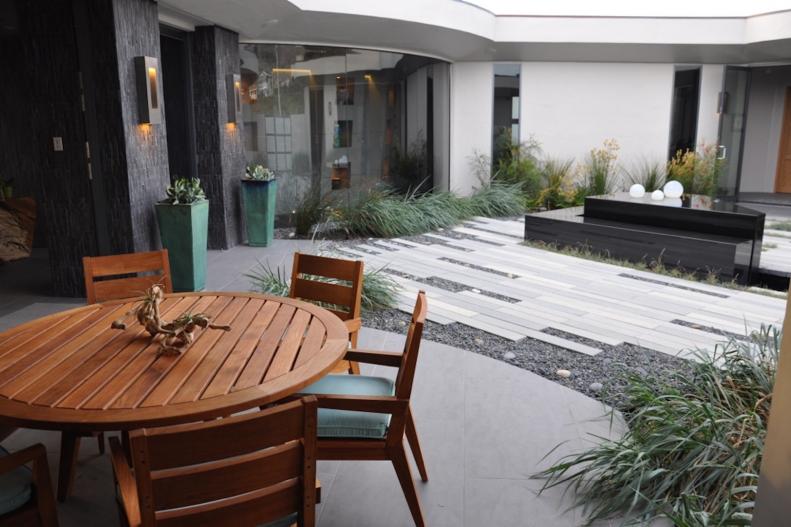 The courtyard of a California beach home lacked a strong connection to the entryway. For an update that maintained the modern look, Jeffrey Gordon Smith Landscape Architecture created a unique area with a narrow, staggered pavers and pebbles in gray tones, plus a custom water feature and tall planters.