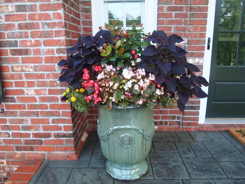 A glazed ceramic pot filled with annuals can be a wise and beautiful investment for your doorway. A decorative planter of this size and weight - it took three people to carry it onto the porch and position it with Pot Pads underneath for protection - can cost a few hundred dollars. A matching container on the other side of the door helped create a new focal point for the entryway.