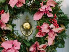 A foraged greenery wreath with tallow berries, 'Carolina Sapphire' cypress, magnolia, Scotch pine, nandina berries, pine cones, camellia branches and boxwood serves as the perfect base for poinsettias in water picks. The wreath is a festive adornment to the white and pink Southern front porch. Styled by <a target="_blank" href="http://www.cotedesignsevents.com/#!/HOME">Cote Designs</a>.