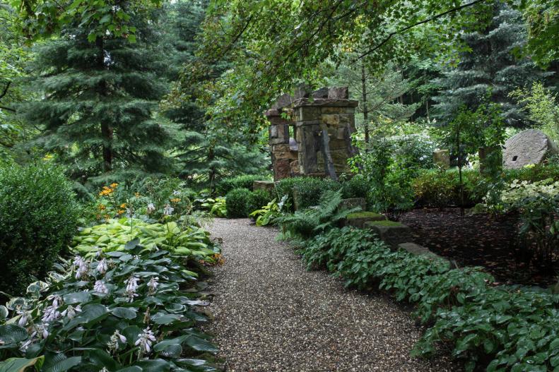 A gravel path winds around to a massive stone arch in the entryway to the &quot;Sun and Moon Garden&quot; in Ohio. Designed by <a target="_blank" href="http://www.miriamsriverhousedesigns.com/">Miriam's River House Designs</a>, the garden and walkway won a 2014 Association of Professional Landscape Designers award.