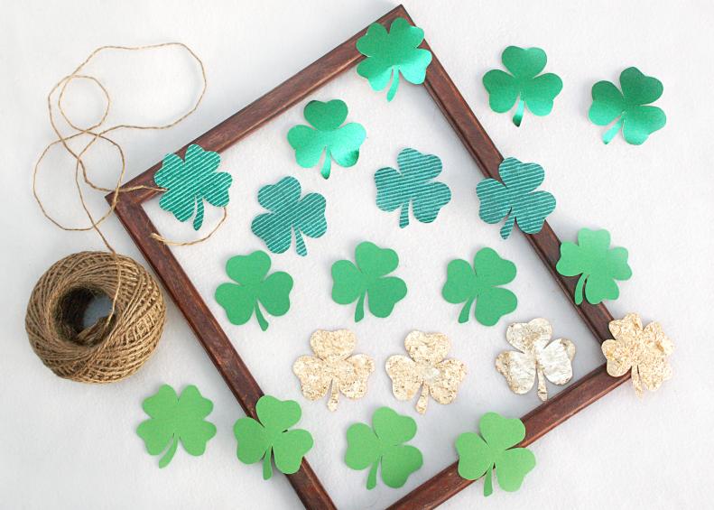 To create your framed clover you will need an empty frame, twine, hot glue and a variety of small clover shapes cut from stiff paper like card stock. Look for different colors, texture and patterns of paper to make your finished piece more interesting. Look for precut clovers at your local craft store, or create your own.