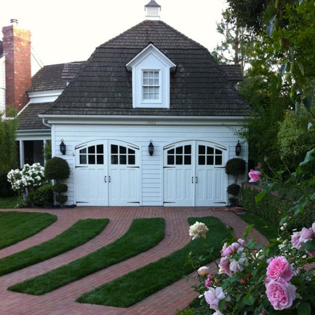 A boxwood hedge and grass accents transform a large garage into a cottage.