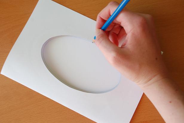 Begin with a blank, folded greeting card. If it doesn't already have a window cut one in the shape and size of your choosing into the front. Trace this window onto the inside of your card. This shape will allow you to know what will show through when the card is closed.