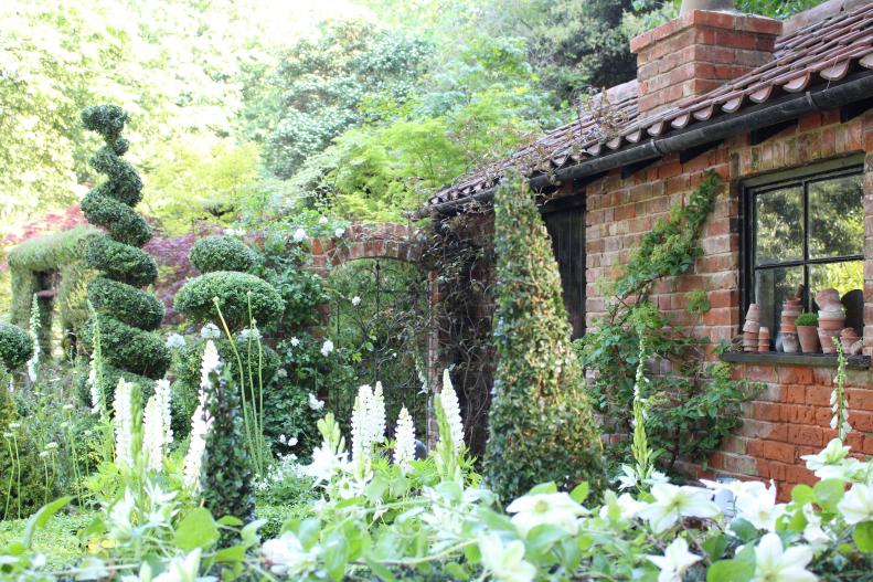 The Topiarist Garden at West Green House was created by designer Marylyn Abbott to suggest the tended garden of a gardener at an English manor house indulging a love of both topiary and perennials in a small, cozy garden space.